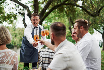 Here's your drink. Group of adult friends have a rest and conversation in the backyard of restaurant at dinner time