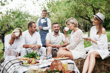 Joyful mood. Group of adult friends have a rest and conversation in the backyard of restaurant at dinner time