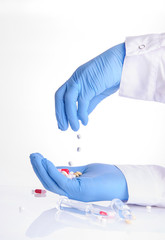 the hands of a doctor holding pills of different color; ampoules with medicine