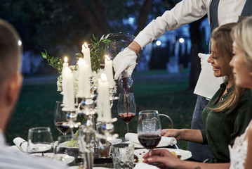 Peaceful moment. Group of adult friends have a rest and conversation in the backyard of restaurant at evening time