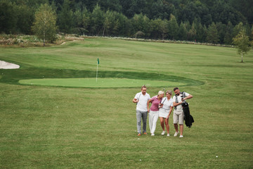 Group of stylish friends on the golf course learn to play a new game. The team is going to rest after the match
