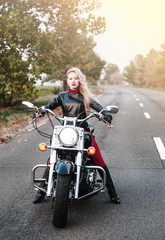 Fototapeta na wymiar A stylish biker woman posing outdoor with motorcycle. 
