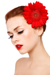 Fototapeta na wymiar Portrait of young beautiful woman with winged eye make-up and red flower over white background
