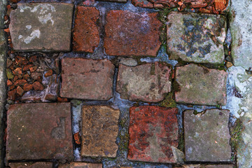 Obraz premium An old red brick wall, with peeling plaster and a covered stone.