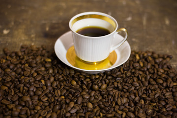 Fototapeta premium cup of coffee with beans on wooden table