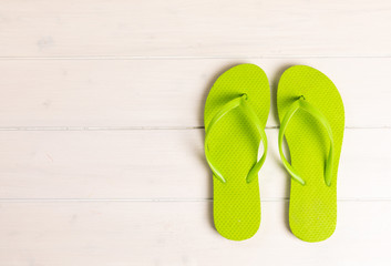 green flip flops on white wooden background with copy space