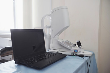 Window at background. Workplace of the doctor. Laptop and ophthalmic equipment on the table