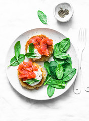 Potato cakes with smoked salmon, sour cream and spinach on a light background, top view. Delicious snack, tapas, brunch