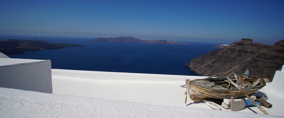 Panoramic view of the Caldera with an old boat in Oia, in Santorini