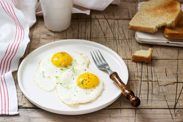 Breakfast of fried eggs, bread toasts and coffee on a wooden table. Rustic style.