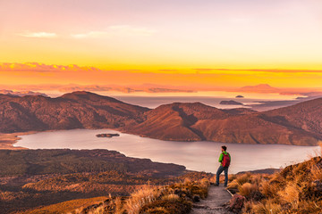 Hiking wanderlust adventure man hiker alone looking at sunset nature landscape of mountains and lakes during summer. Travel outdoors freedom lifestye.