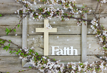 Wooden cross and the word Faith hanging on rustic background with floral border