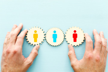 wooden cogwheels puzzle blocks with people icons over wooden table ,human resources and management...