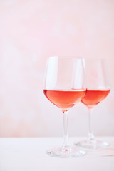 Summer drink. Glass of rose wine on white marble table over pink background with copy space for text. Selective focus.