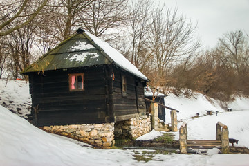 Old abandoned water mill near the lake Snowy cloudy day, sunset