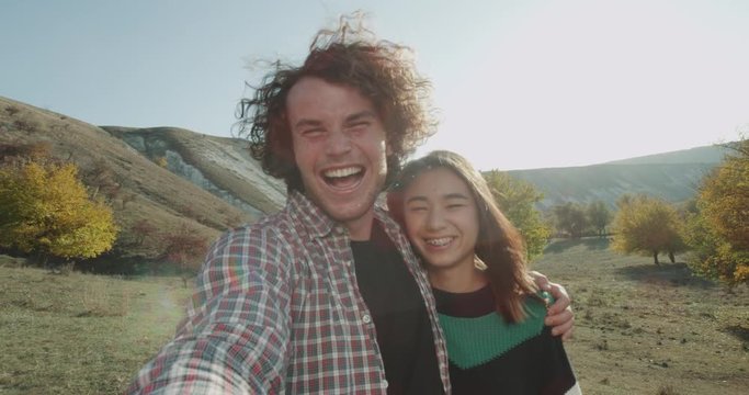 Middle of nature beautiful different races couple have a trip together they taking camera ,smiling and making funny faces in front of the camera. 4k
