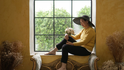 Asian senior woman sit in Europe style window sunlight, luxury travel - obrazy, fototapety, plakaty