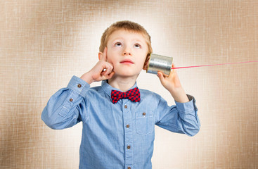 thinking young boy is  listening with tin can telephone