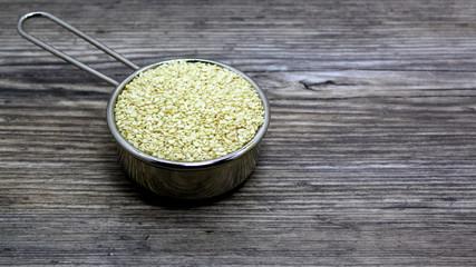 bucket with sesame on the table.  sesame seeds scattered on the plate on wooden background