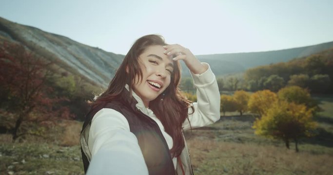 In the top of mountain a good looking girl with beautiful teeth taking a selfie video and shows the landscape view.