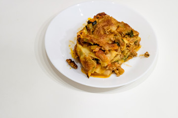 Closeup of Italian lasagna bolognese with cheese crust, homemade on plate, isolated white table background
