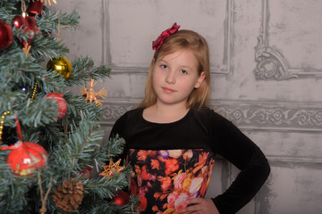 girl blonde child in black with red dress in christmas by the christmas tree