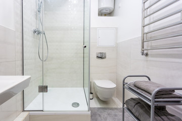 toilet and detail of a corner shower cabin with wall mount shower attachment