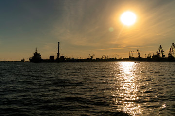 Fototapeta na wymiar Silhouettes of seaport cranes at sunset. Evening panorama of the cargo port, Ukraine, Kherson