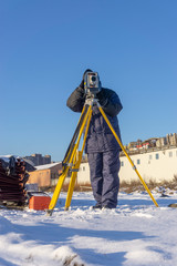 Surveyor in the winter on the construction site conducts topographic and cadastral work