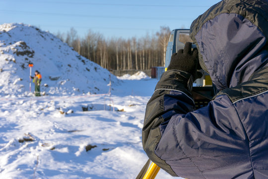 Surveyor in the winter on the construction site conducts topographic and cadastral work