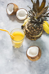 Pineapple, banana and coconut cocktail or juice in glass on concrete background