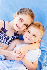 The older sister hugs her younger brother on the beach