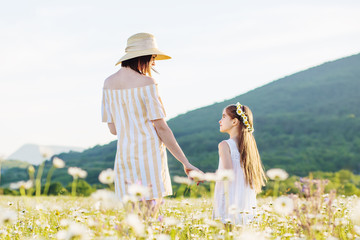 Mother and daughter in  field of daisies. Beautiful family in nature.