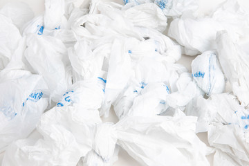 A composite of a bunch of used and non-biodegradable white plastic bags with blue printed markings.