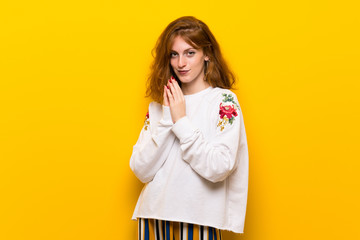 Young redhead woman over yellow wall scheming something