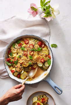 Zucchini and Mint Gratin in pan with hand spooning out