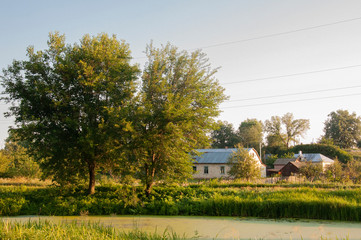 Light clouds in the warm summer sky over village with small light houses from brick far away in the forest. Small lake is near. Sunrise. morning.Travelling on the suburb roads