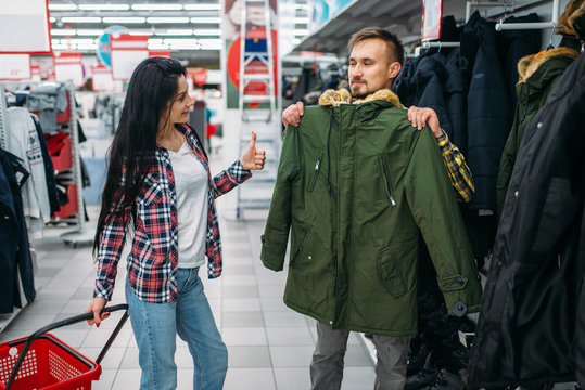 Young couple choosing warm clothes in supermarket