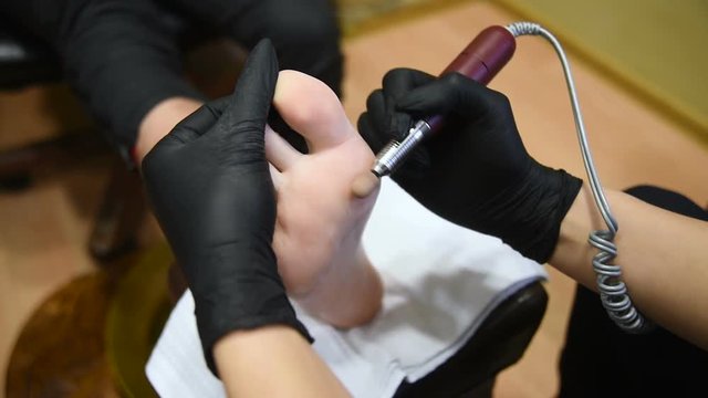 a young woman makes a man pedicure in the background of a beauty salon. Nail care