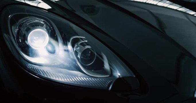 Close up of details of switched on headlights of anonymous prestigious luxury modern car. Shot in 8K. Concept of passion for driving cars and engines, car dealerships, used cars,luxury cars, auto dial