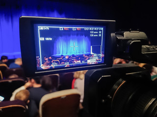 LCD display on digital camcorder. Children and parents in the auditorium of the theater before the...