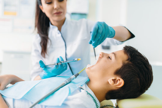 Injection of anesthesia, boy in dental chair
