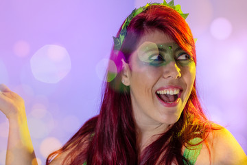 Carnaval Brazil. Surprised and excited. Portrait of redheaded woman and green makeup mask. Colorful background. Carnival concept, fun and party.