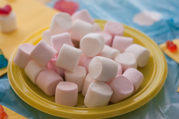 closeup of marshmallows in plastic plate on festive table background