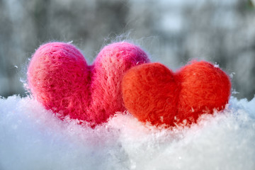 Fototapeta premium Two wool red and pink hearts standing on the white fluffy snow