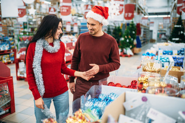 Young couple chooses christmas tree toys in shop