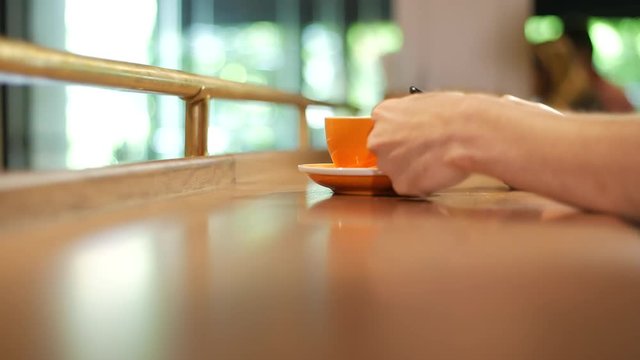 Male hands holding cell phone and drinking coffee from an orange cup, depth shot