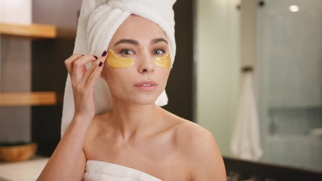 woman putting on eye treatment mask on her face / Skin-care