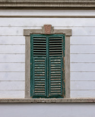 A green window blind with beautiful lines on a building in baroque style