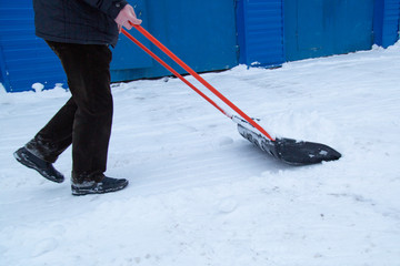 Clearing snow with a shovel in the winter on the street 